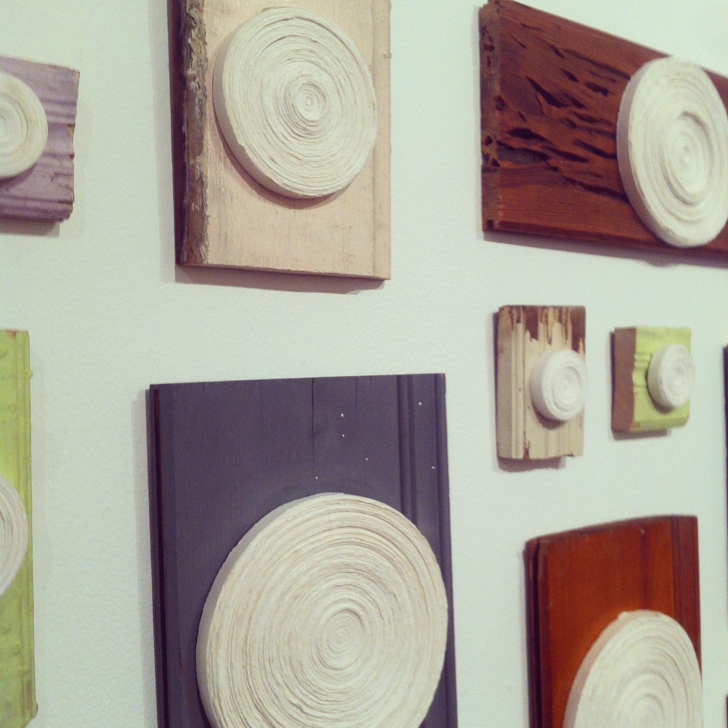 Wall display of wooden panels with carved circular rosette sculptures in various earthy colors